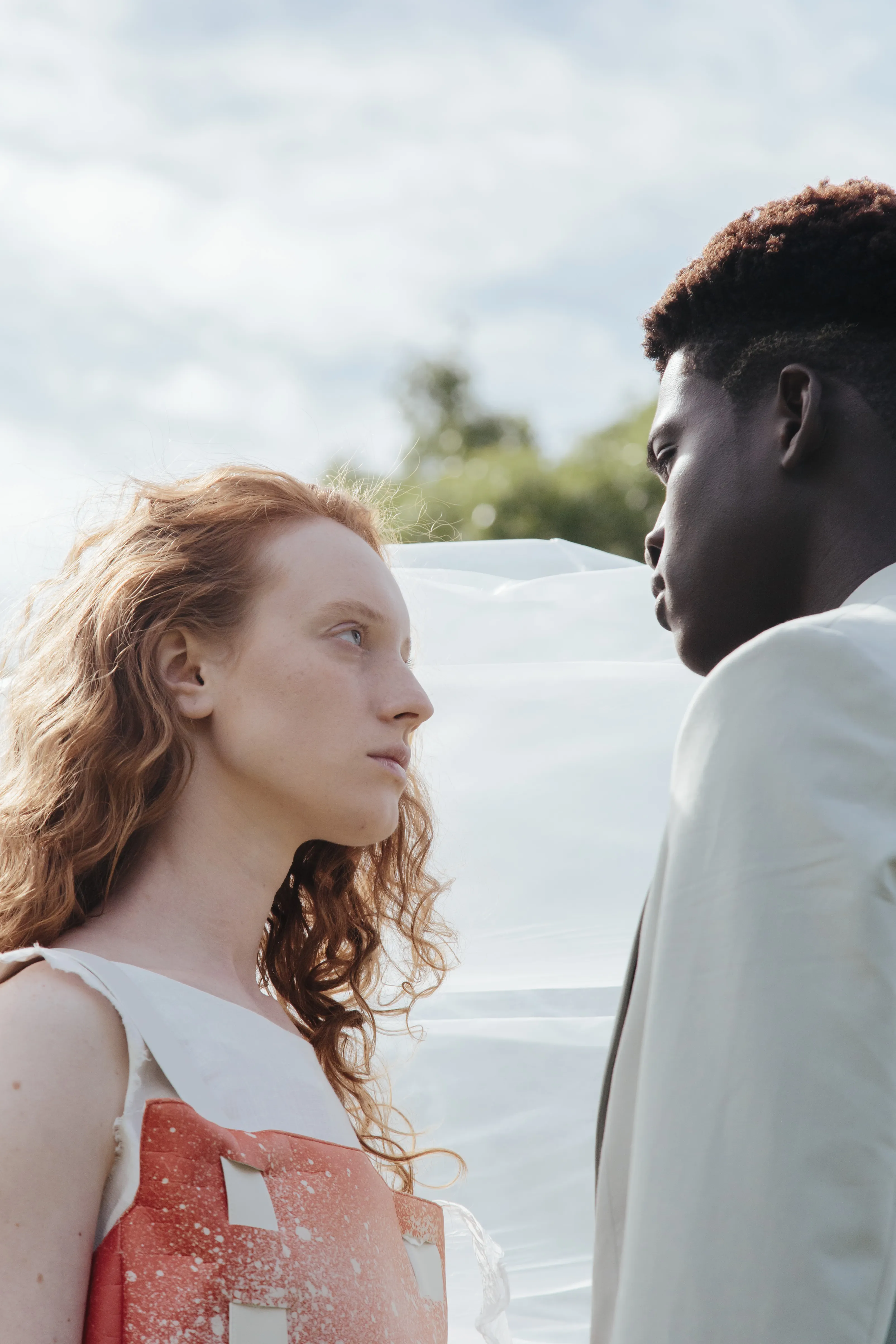 Diverse couple looking thoughtfully into each other's eyes outdoors
