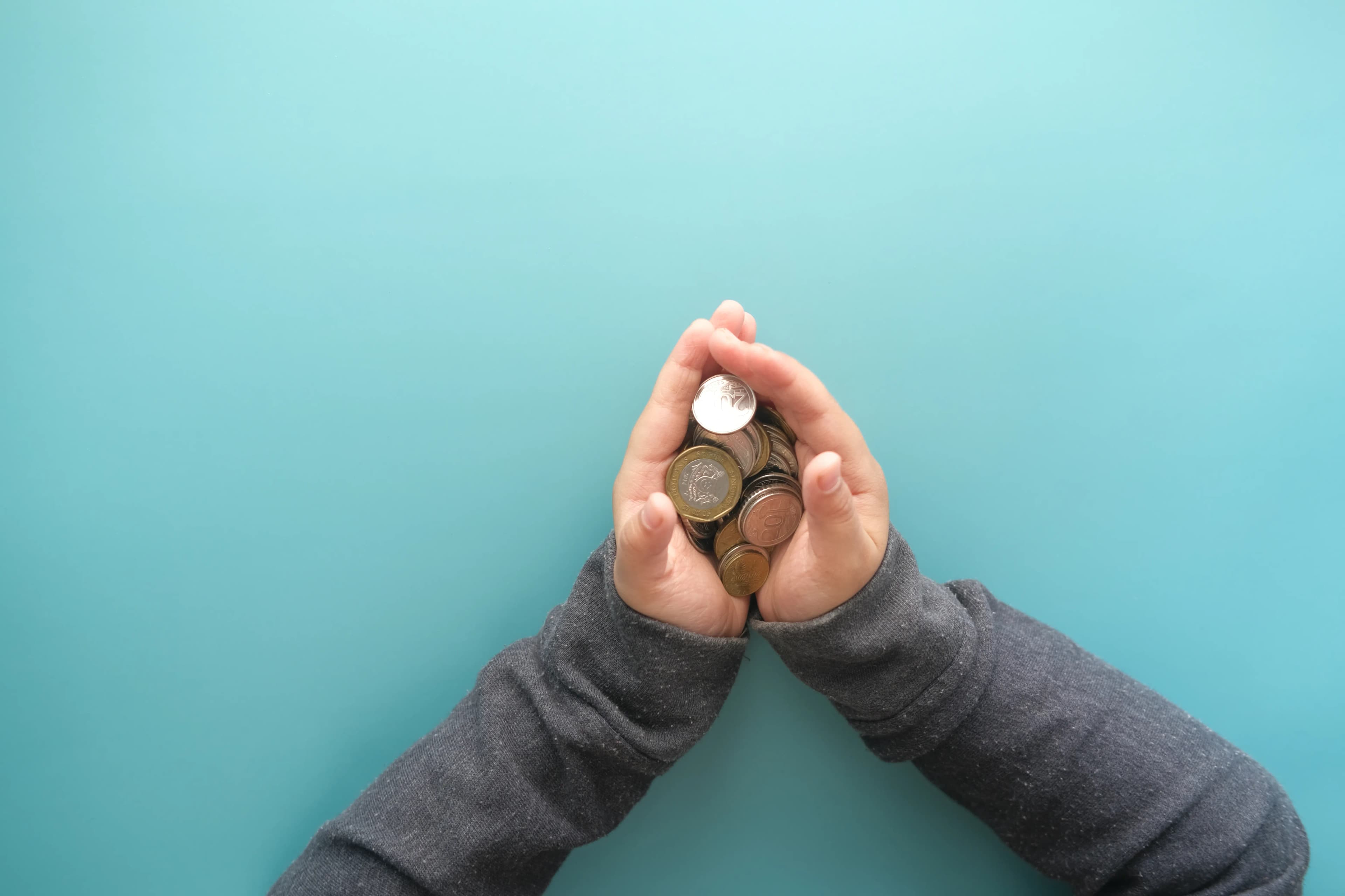 Hands holding stacks of coins against a blue background