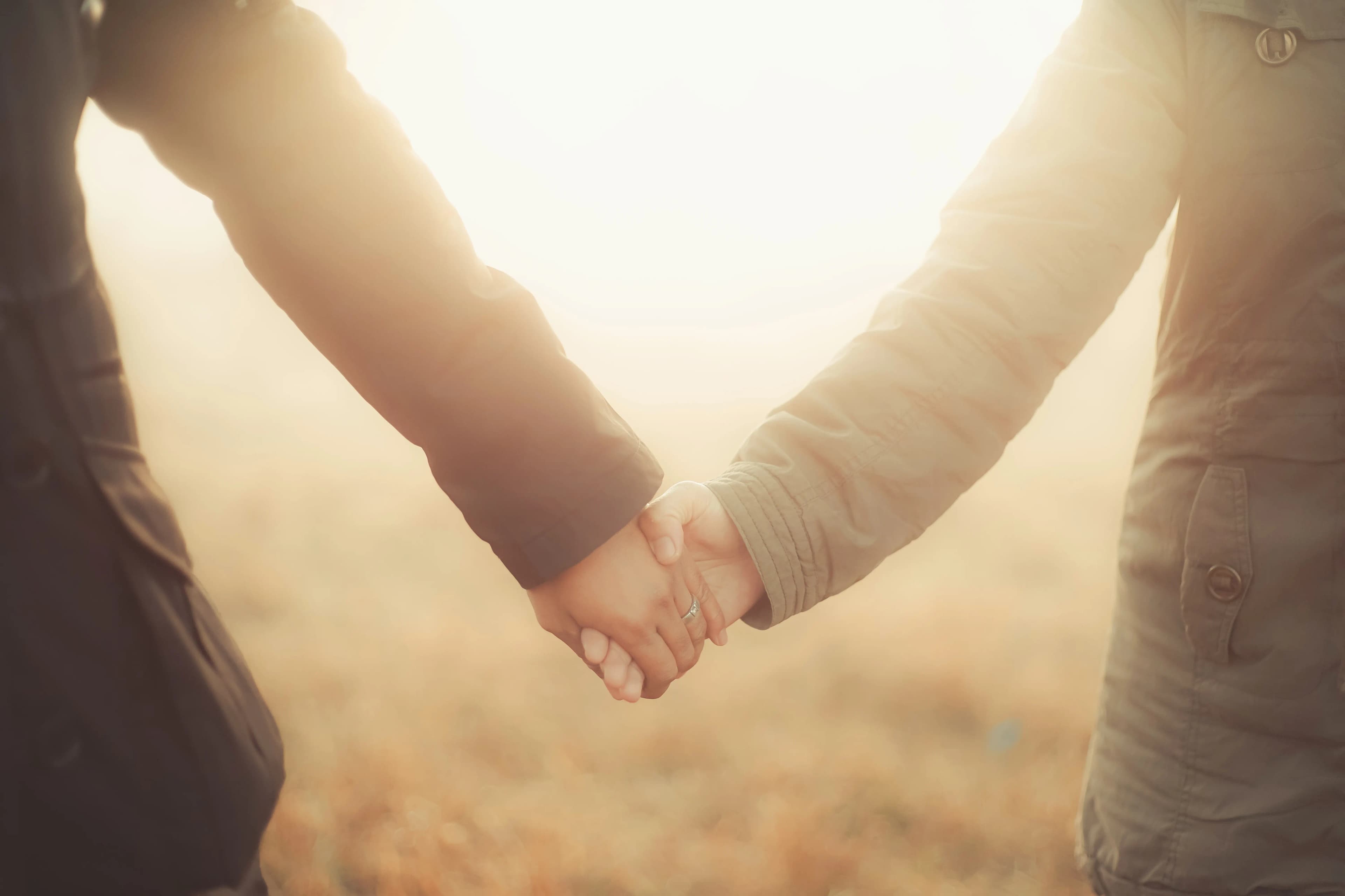 Close-up of two people holding hands in warm evening light