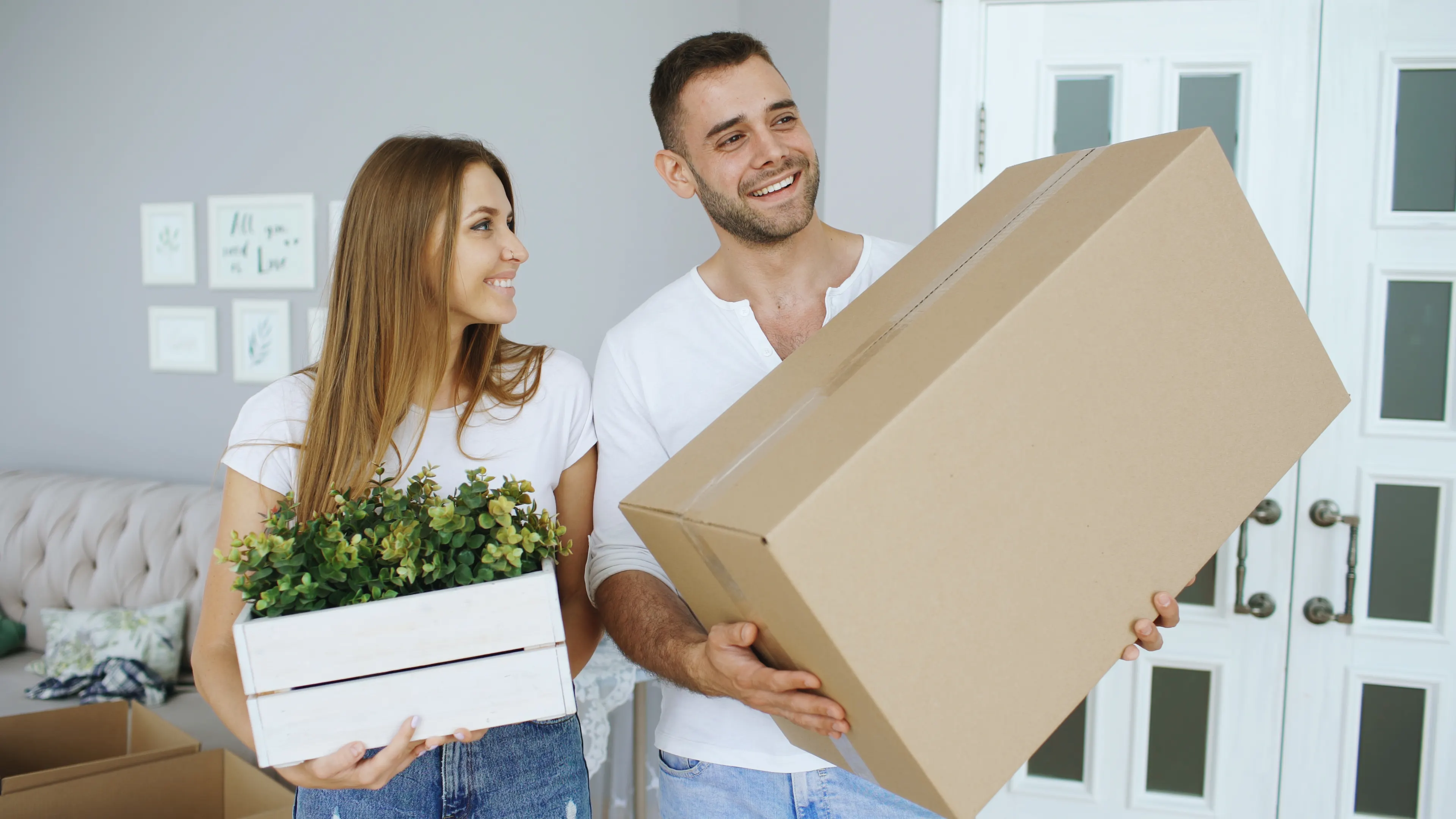 Couple carrying their belongings and plants into a new home