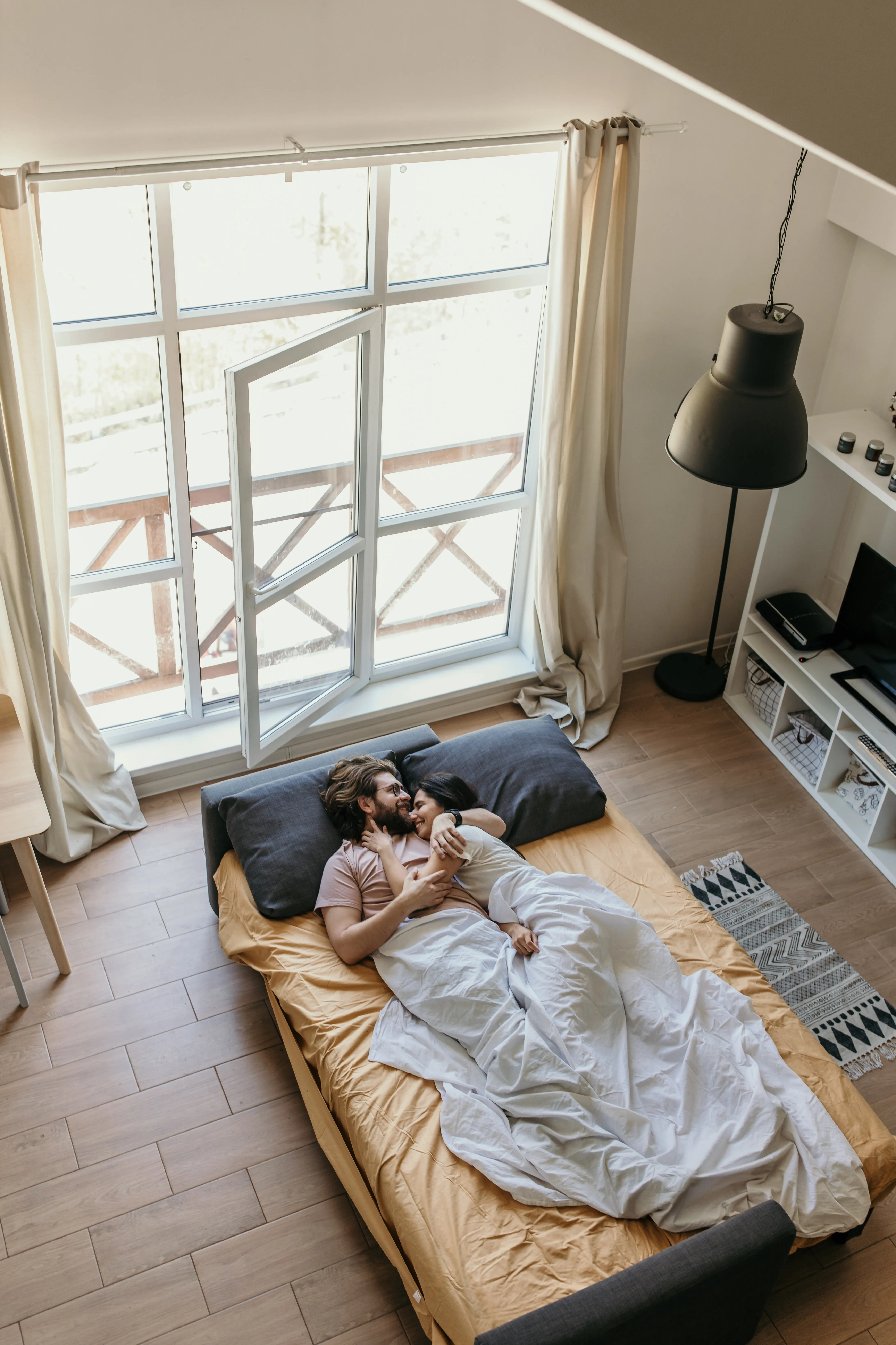 Couple resting together in a bright bedroom with natural light