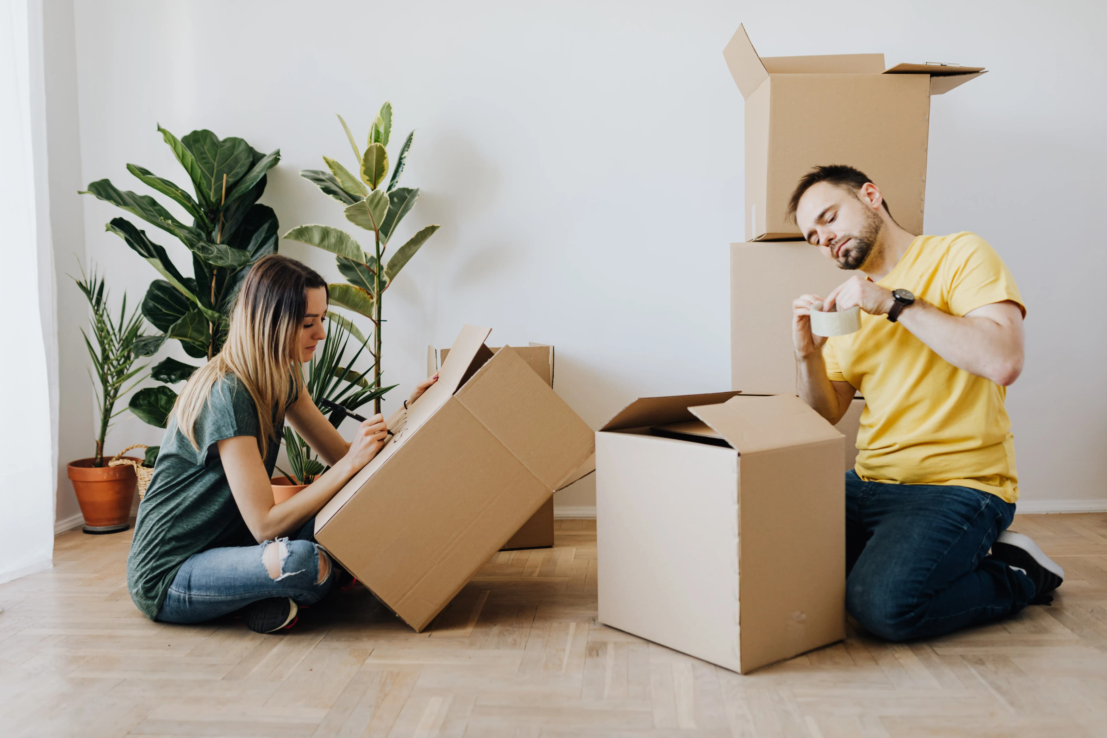 Couple sorting moving boxes on the floor of a shared home