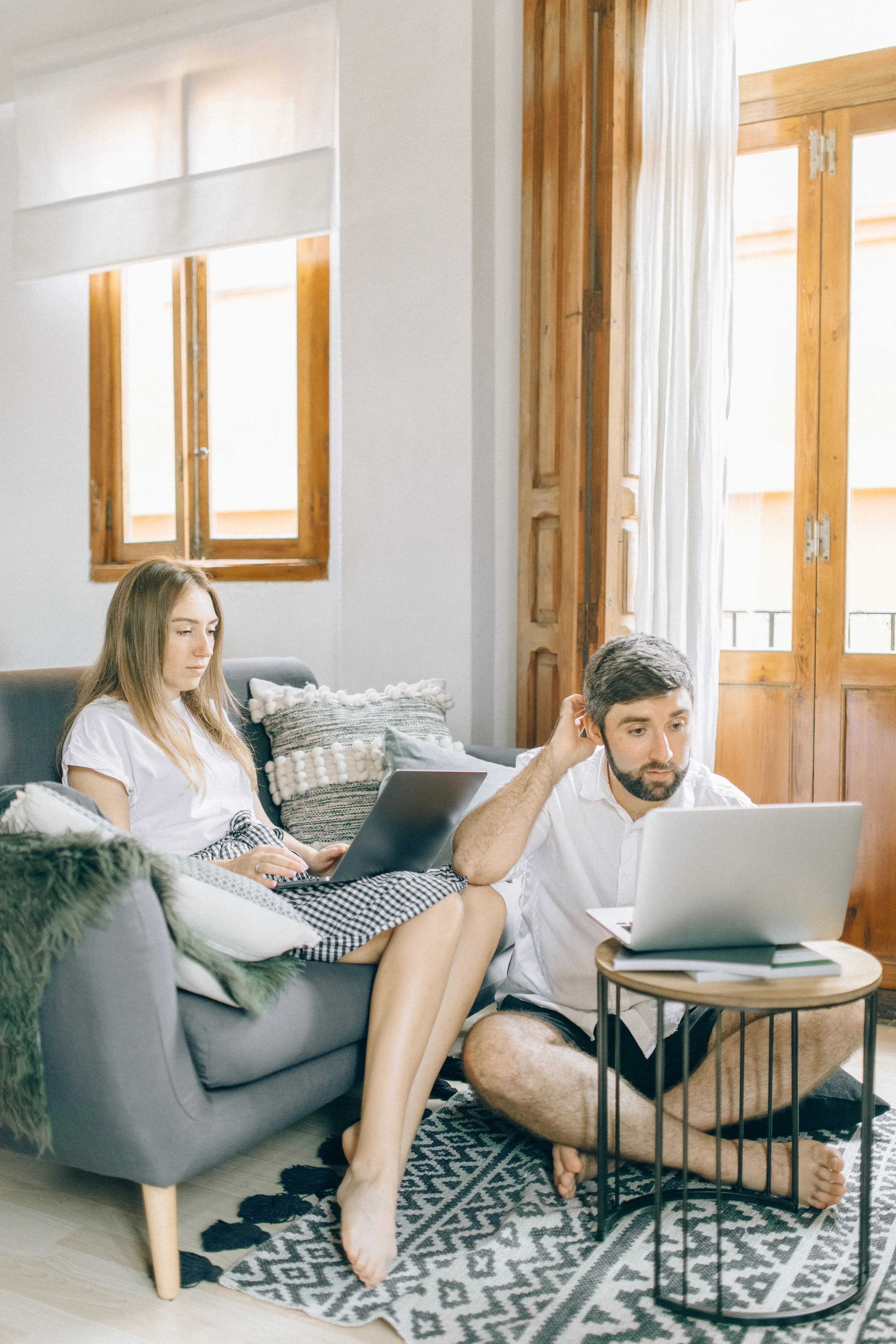 Couple working separately with laptops in the same living space