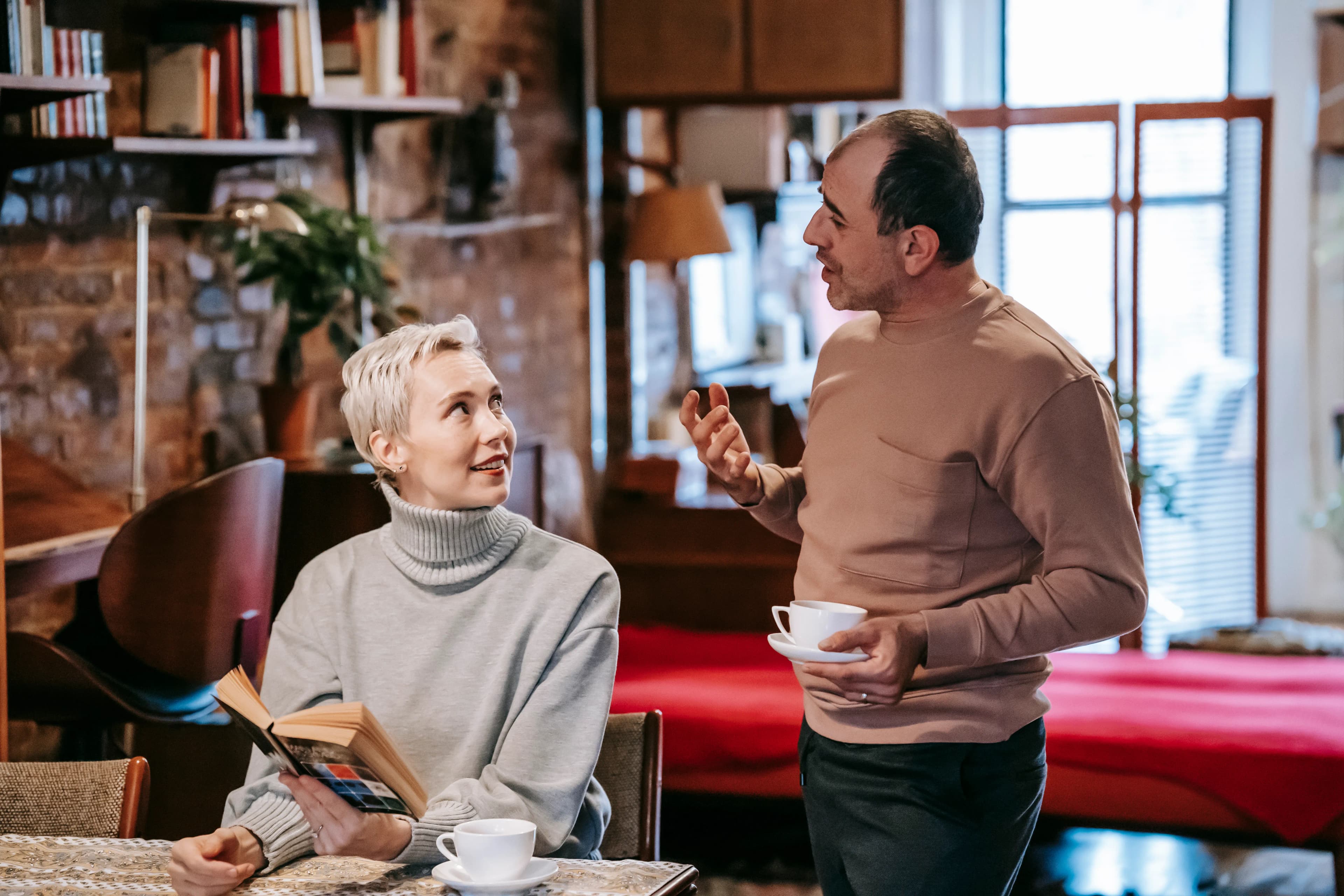 Diverse couple discussing a book together over coffee at home
