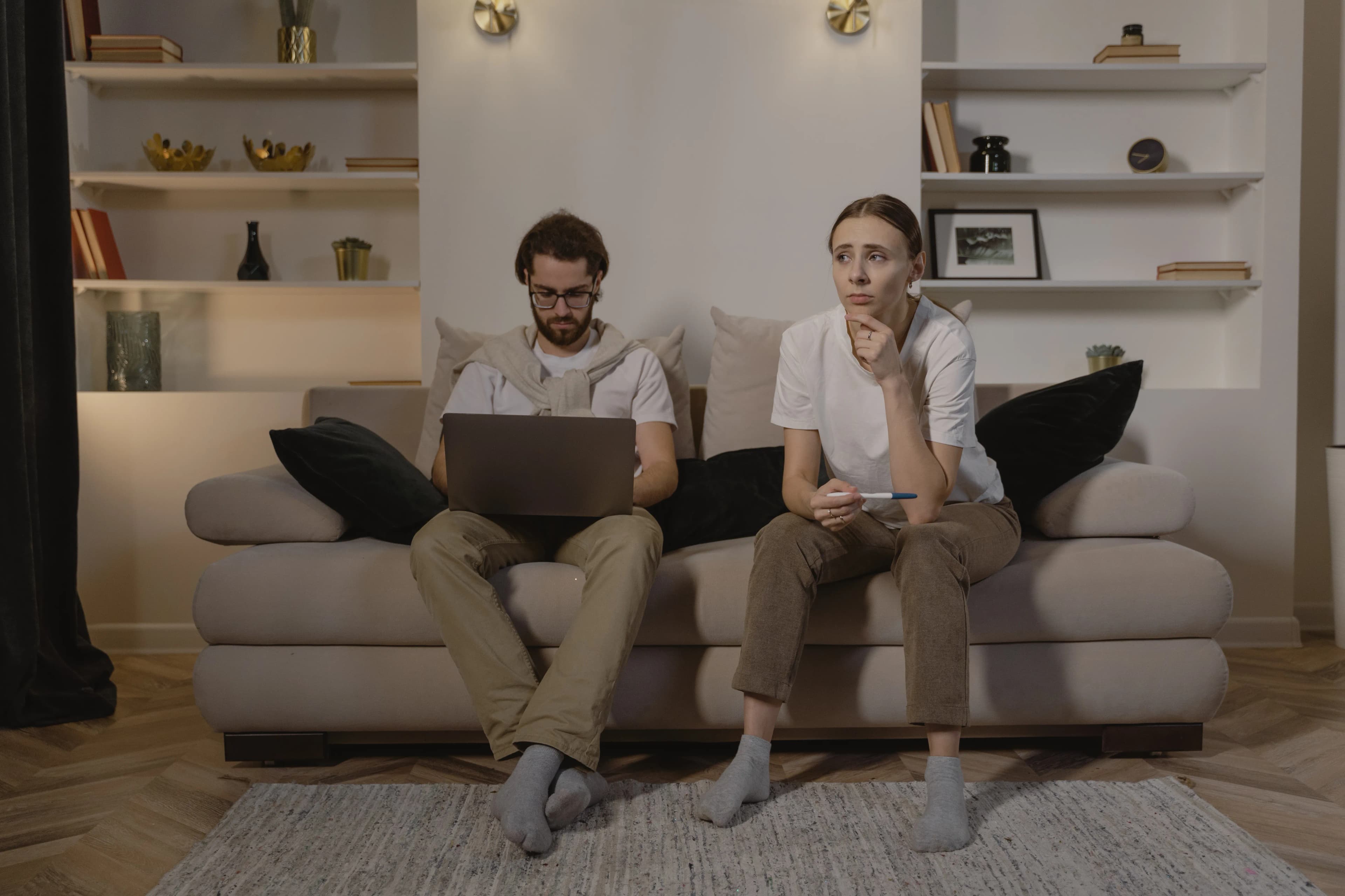 Two partners sitting together in a living room, one using a laptop