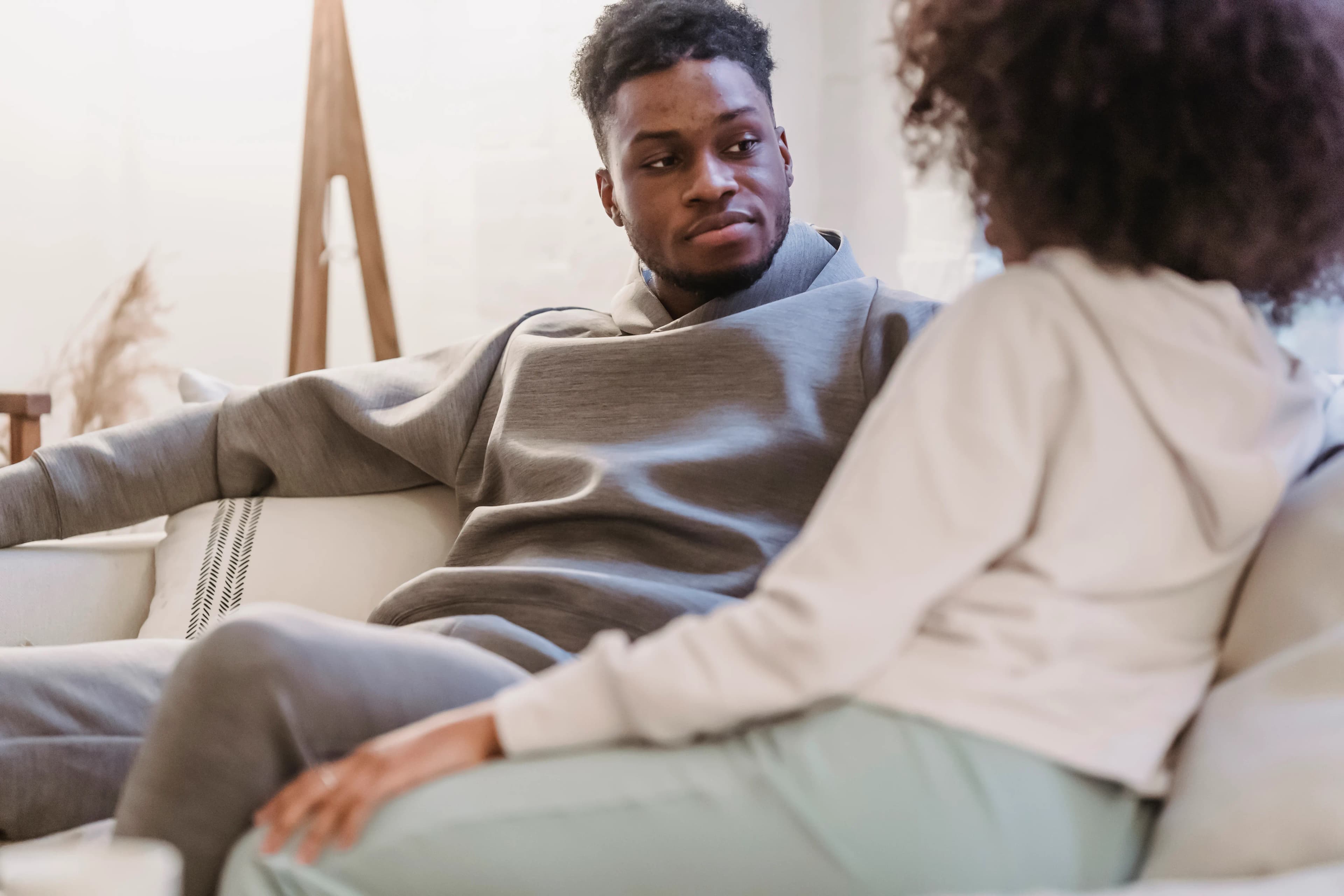 Couple listening to one another on a sofa at home