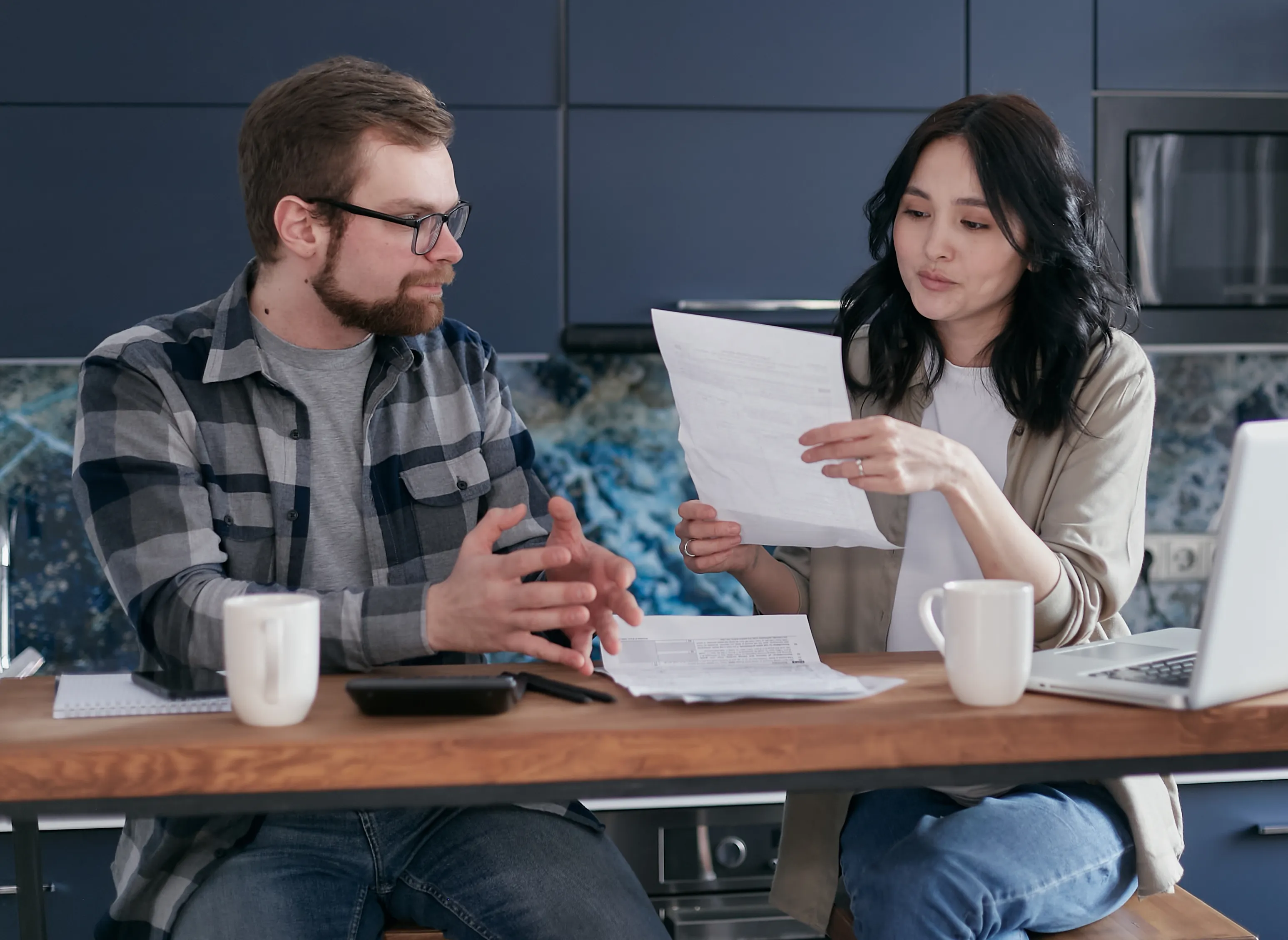 Couple discussing household costs at a laptop
