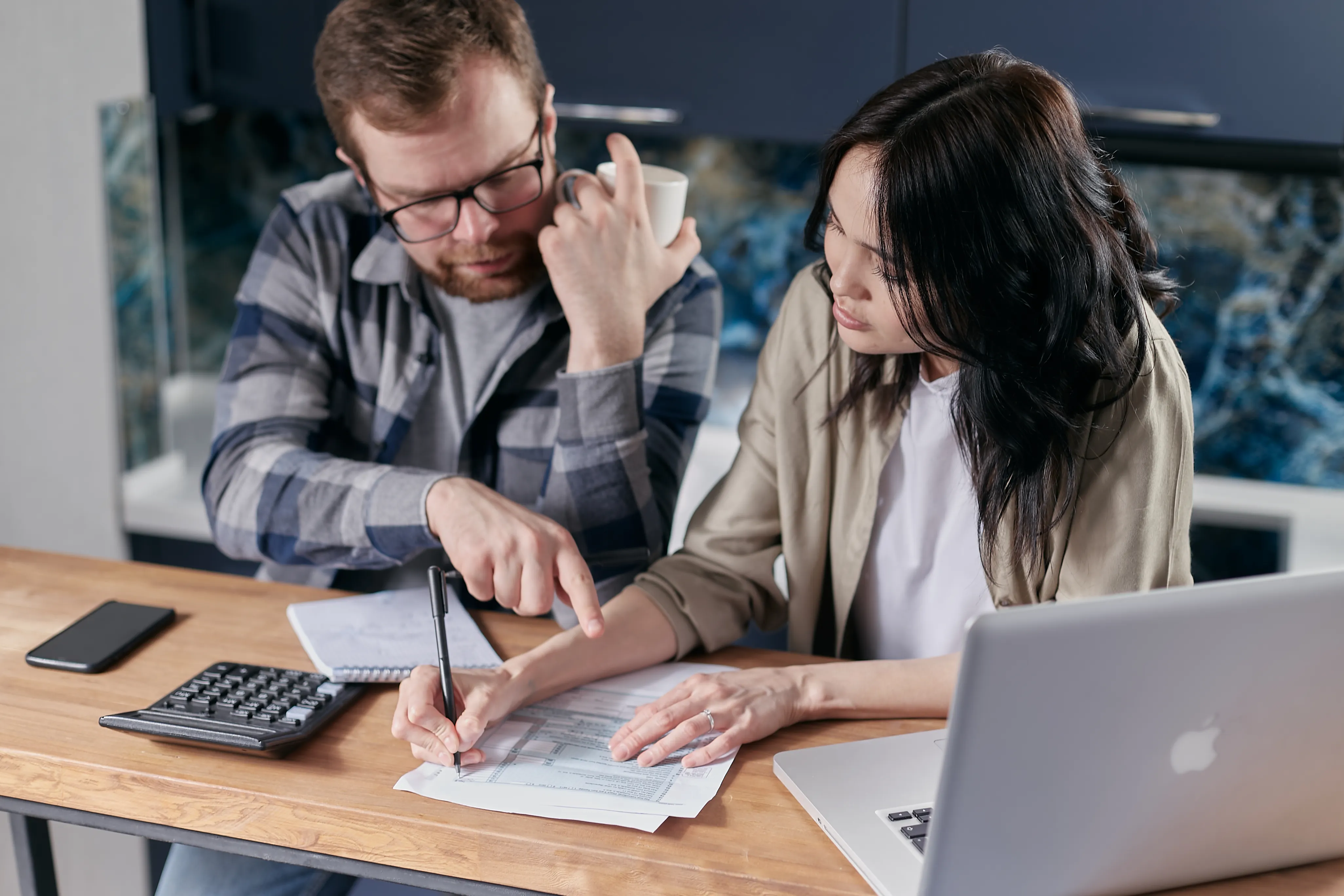 Couple reviewing household bills with a calculator and laptop