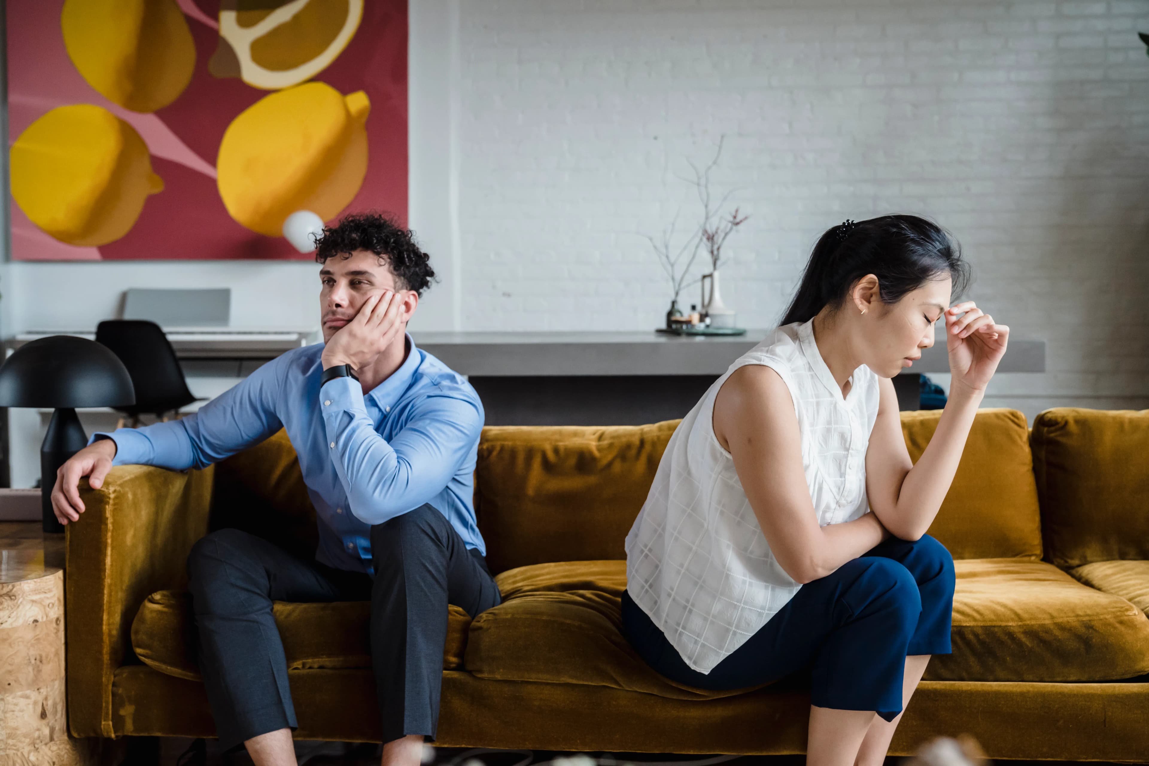 Two partners sitting apart on a sofa, reflecting quietly
