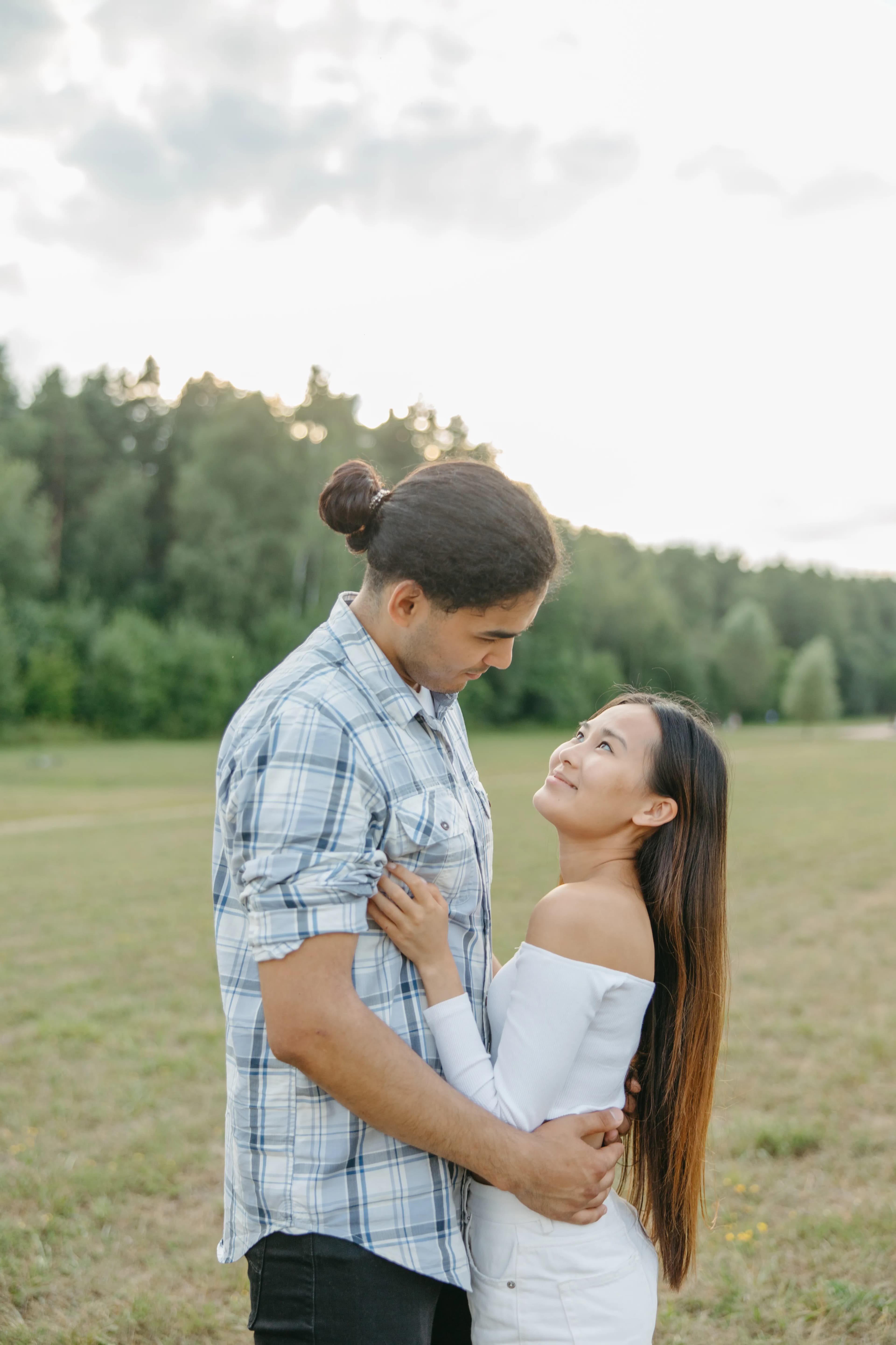 Multiracial couple embracing in an open green field