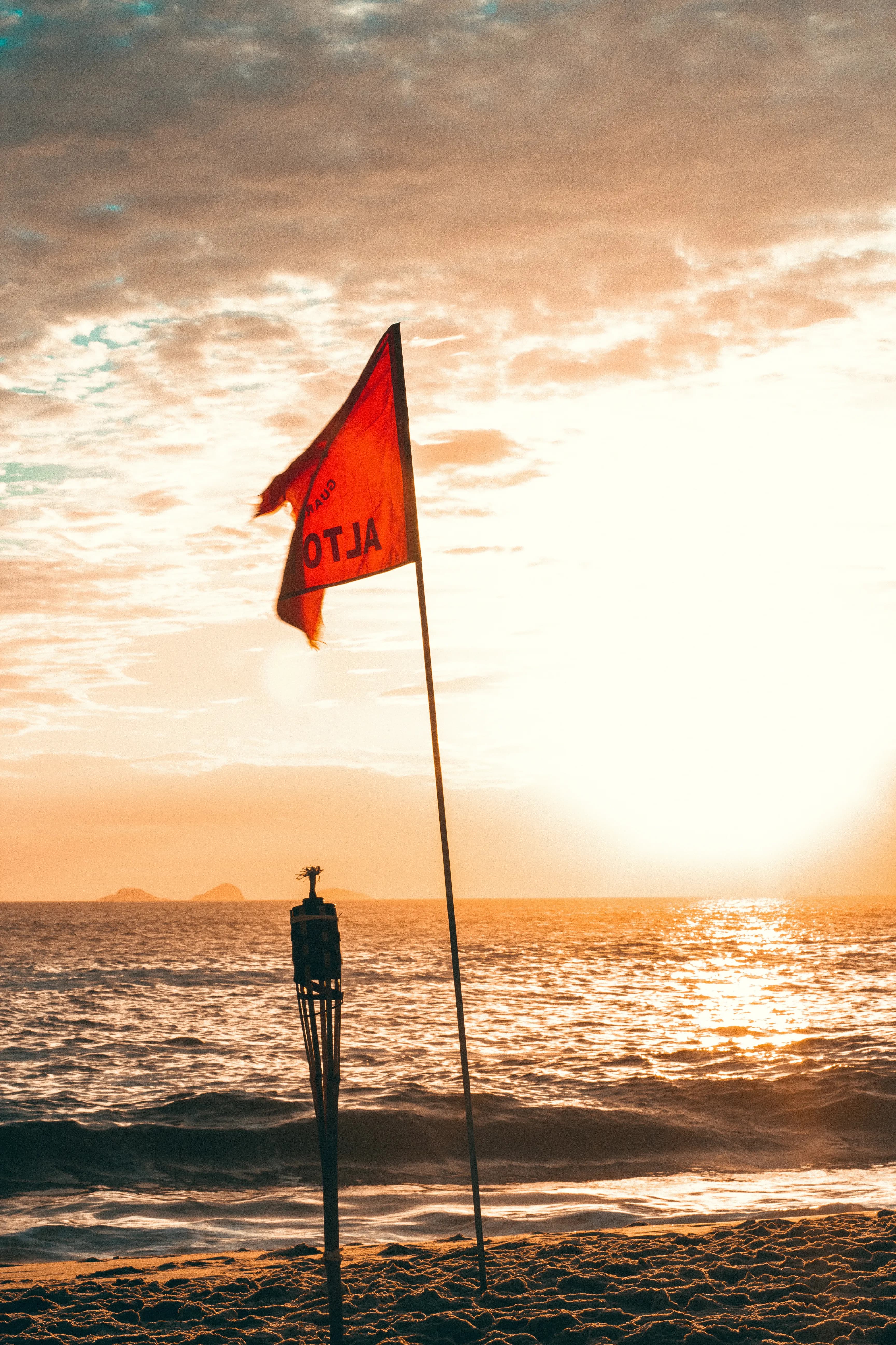 Red warning flag flying above an open beach