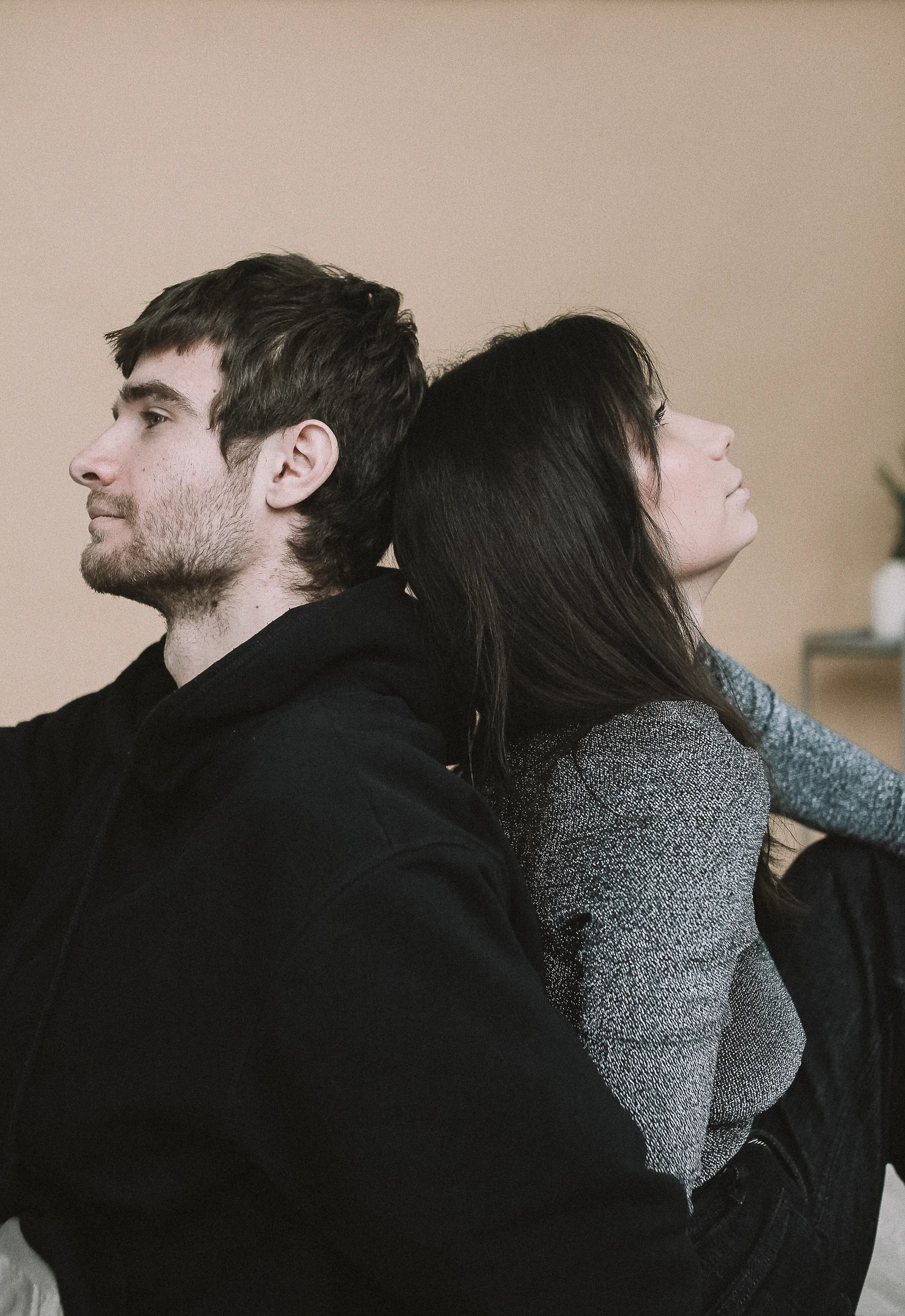Two people sitting back to back in a thoughtful moment