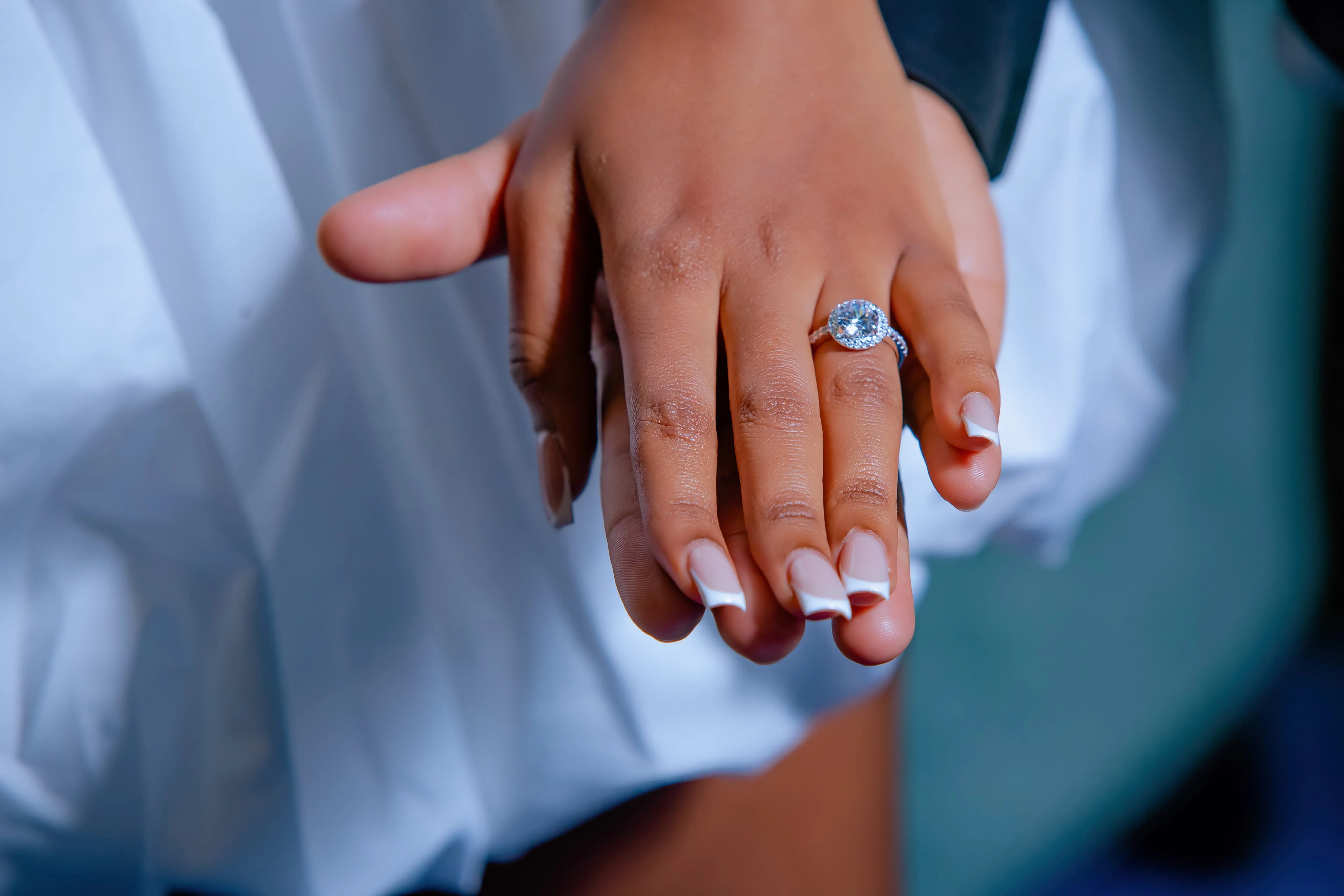 Two hands showing an engagement ring in close-up