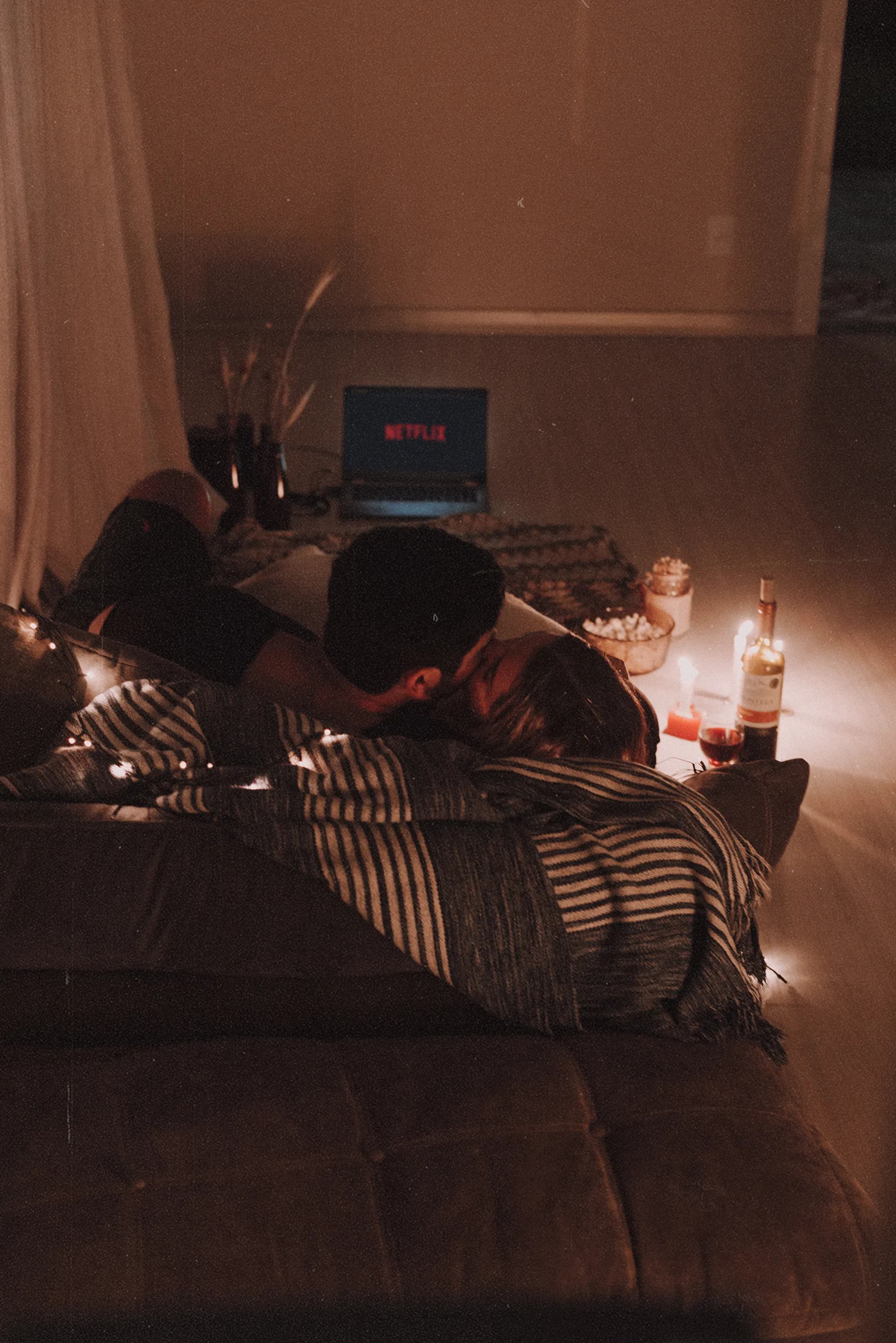 Couple sharing an affectionate moment on a sofa by candlelight