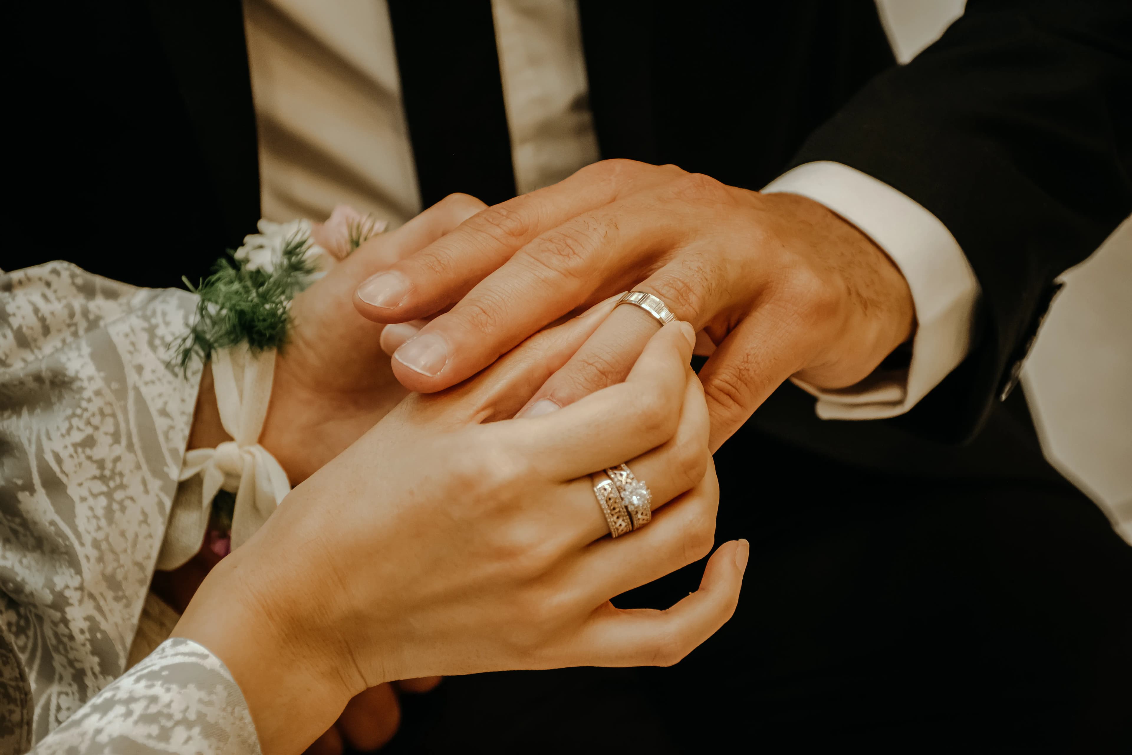 Close-up of hands exchanging wedding rings at a ceremony