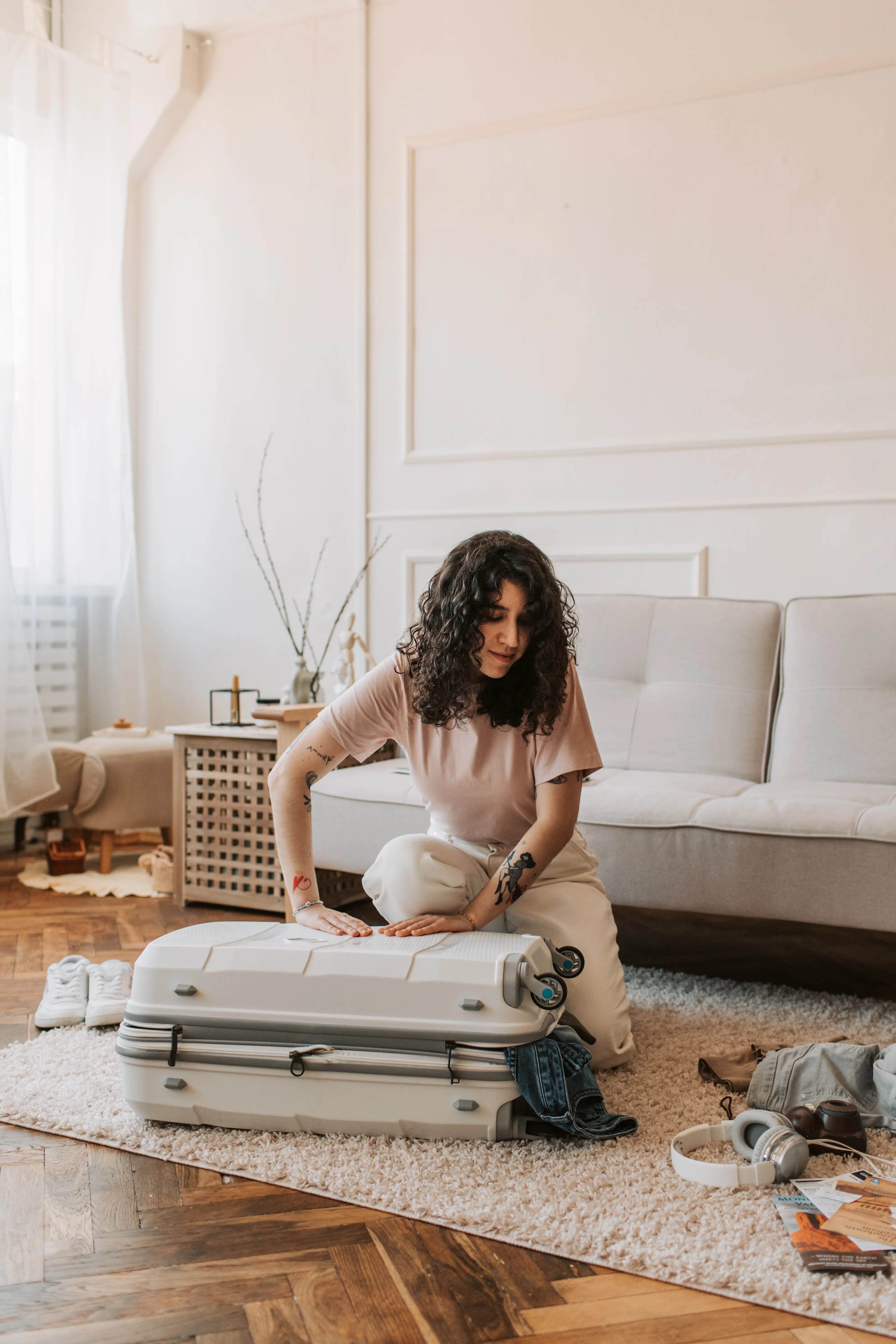 Person packing a suitcase alone in a sunlit living room