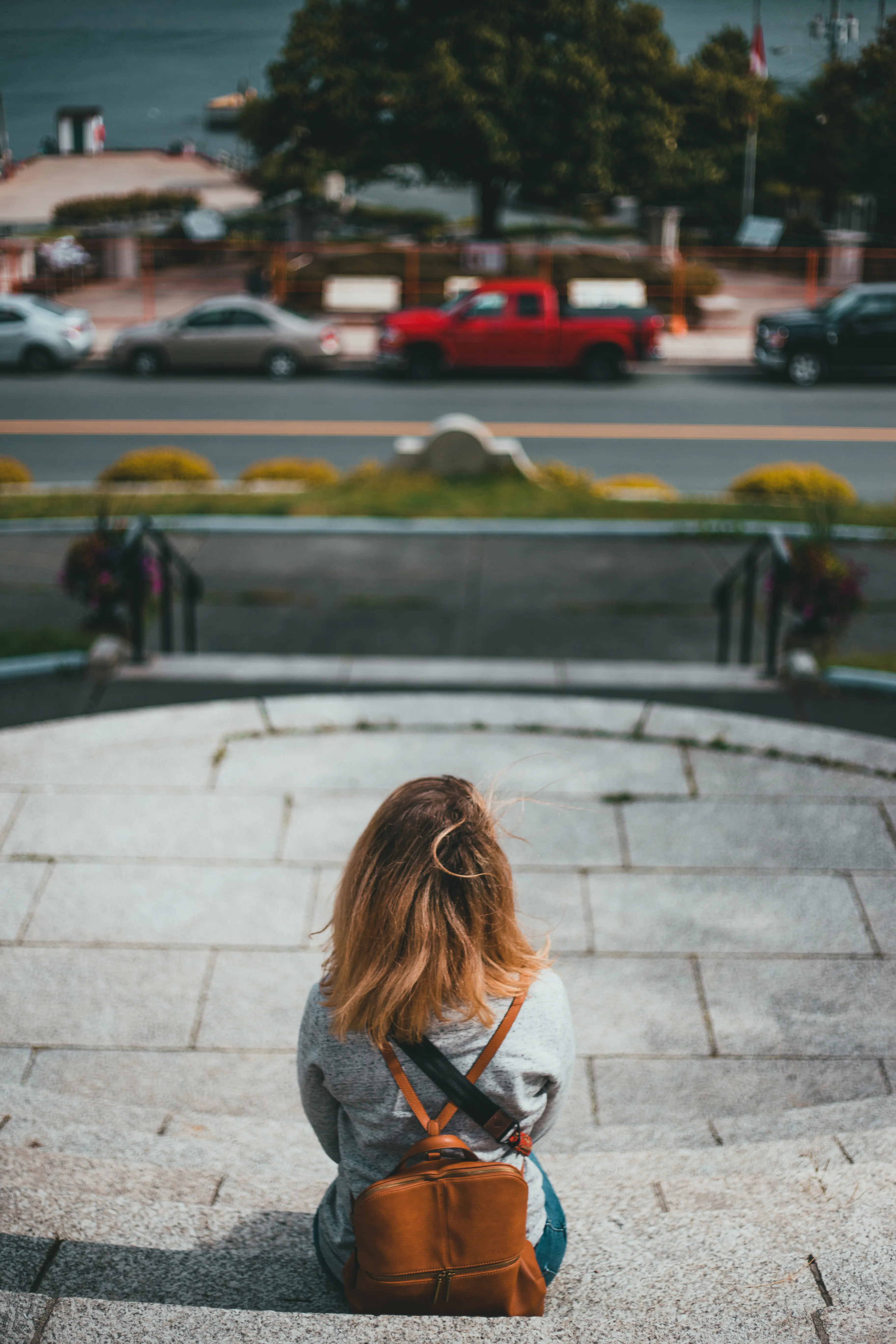 Person with a backpack sitting on steps in quiet reflection